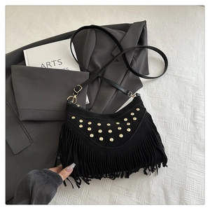 Close-up of black suede crossbody bag featuring golden studs and long fringe tassels