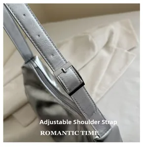 Detail of adjustable silver shoulder strap with metallic buckle on a textured crescent bag