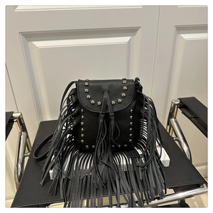 Detail of black crossbody bag featuring silver studs and bohemian long fringe tassels