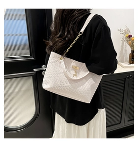 Detail showing white woven texture shoulder bag with gold chain and deer pendant