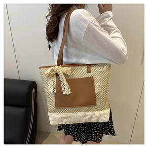 Close-up of woven straw tote with faux leather pocket and delicate lace bow detail