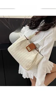 Detail view of woven straw tote bag featuring brown leather flap and golden metal lock