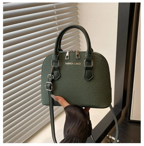 Close-up of dark green woven shell bag with silver FASHION & BAGS logo detail