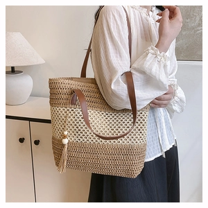 Detail of straw tote bag with color blocking design and leather shoulder straps
