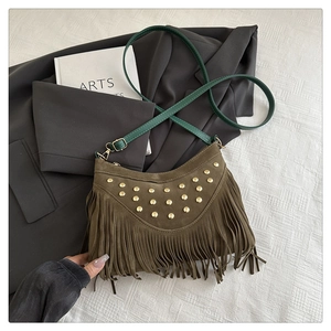Detail of brown suede crossbody bag with gold rivets, green strap and stylish fringe