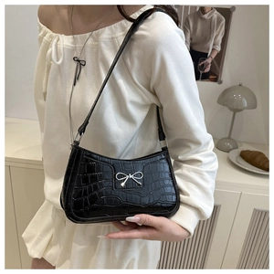 Close-up of black crocodile pattern shoulder bag with a silver metal bow detail