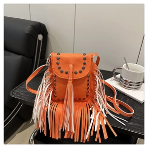 Detail of bright orange fringe crossbody bag with metallic studs on leather texture