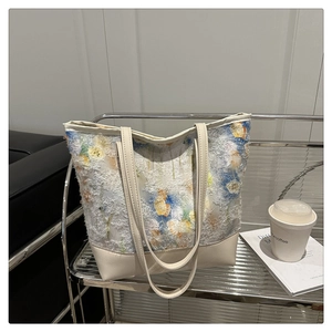 Detailed view of large floral print tote bag with frayed texture and faux leather straps