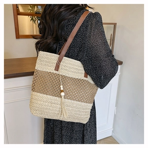 Detail of hand-woven straw tote with tri-color blocks and brown leather strap for summer