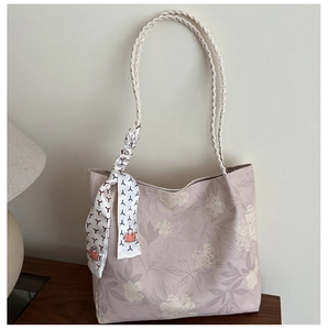 Detail of floral tote bag with woven rope handles and silk scarf on wooden table