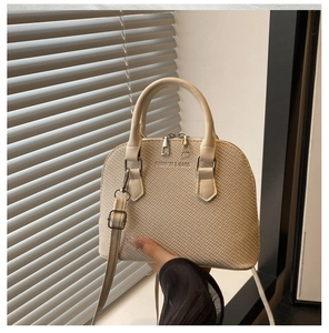 Detailed view of beige woven shell bag with leather strap and embossed logo texture