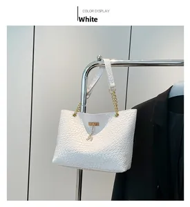 Close-up of white woven tote bag with golden deer charm and chain leather strap