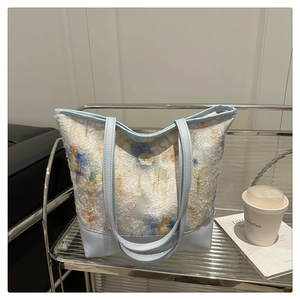 Detail of floral jacquard tote bag featuring light blue leather straps and relief texture