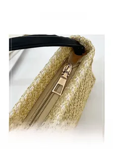 Gros plan sur la fermeture éclair dorée et la texture tissée du sac en paille
