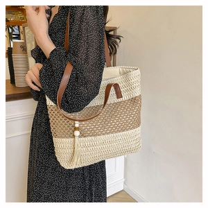 Detail of color-block straw tote bag showing woven texture and brown leather handles