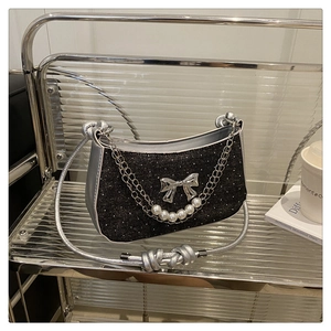 Détail du sac à main noir pailleté avec nœud argenté et chaîne décorative en perles