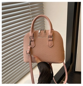 Pink shell handbag featuring woven texture, dual handles, and adjustable shoulder strap