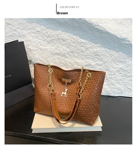 Detail of brown woven leather tote with golden chain strap and deer charm pendant