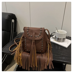 Close-up of bohemian brown leather crossbody bag with vintage studs and long fringe detail
