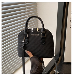 Detail of black textured shell bag with gold embossed text and premium metal zipper