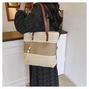 Detail of summer straw tote with cream and brown stripes and a wooden bead tassel