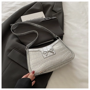 Detail of silver crocodile pattern shoulder bag with a small metallic bow decoration