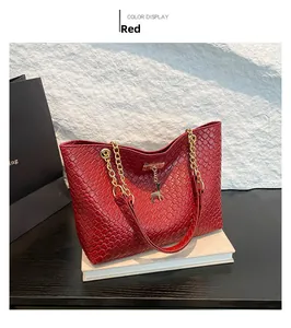 Detail of red woven texture tote bag with gold deer pendant and chain strap