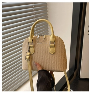 Close-up of beige woven texture and yellow leather trim on a classic shell bag