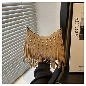 Detail of khaki suede crescent bag with gold studs and long hanging fringe tassels