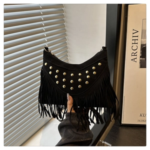 Close-up of black suede crossbody bag featuring tiered fringe and golden rivet details