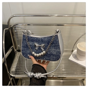 Détail du sac en jean bleu avec boucle papillon argentée, perles et anses nouées
