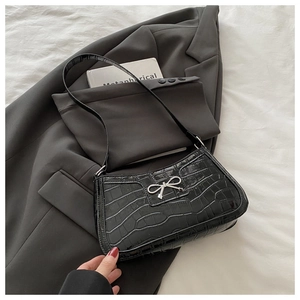 Detailed macro of black crocodile texture handbag with a silver metal bow buckle