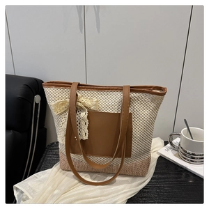 Detail view of the hand-woven beach tote with a lace bow and brown leather handles