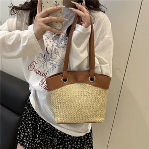 Large straw bucket bag with brown leather handles and natural woven texture for summer
