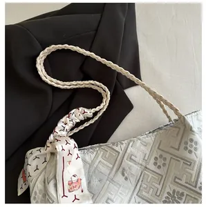 Detail of woven rope shoulder strap and decorative silk scarf on jacquard tote bag