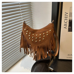 Detail of brown suede shoulder bag with golden studs and bohemian fringe accents