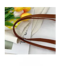 Close-up of brown leather handle with meticulous stitching on a summer straw tote bag