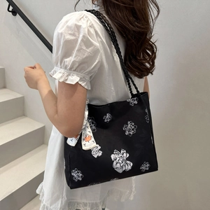 Black floral canvas tote bag with woven handles and silk scarf on a model on stairs