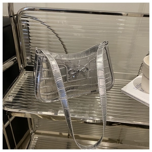 Detail of silver crocodile embossed handbag featuring a polished metal bow fastener