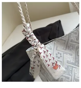 Close-up of silk scarf with red geometric patterns tied on a woven tote bag handle