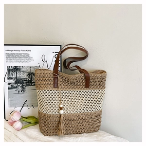 Detail of hand-woven straw tote with contrast stripes, wood bead tassel and brown handles