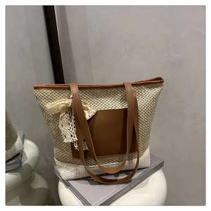 Detail view of woven straw tote bag with PU leather handle and lace bow decoration