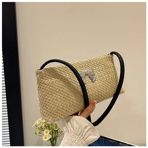 Détail du tissage en paille avec un nœud en métal argenté et une bandoulière en cuir noir