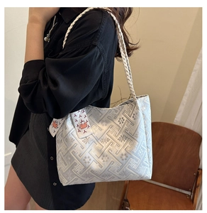 Close-up of silver-gray jacquard tote bag featuring geometric patterns and woven handles