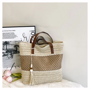 Detail of straw woven tote with brown PU handles and decorative wood bead tassel