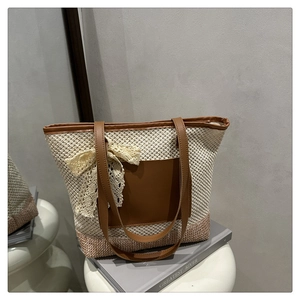Detail of woven straw tote bag featuring contrast base and white lace bow decoration