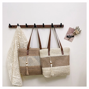 Detalle de bolsos de paja tejida con rayas, asas de PU y adornos de borlas