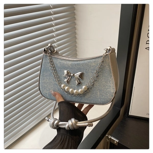 Détail du sac en jean bleu clair avec papillon argenté et décor de chaîne en perles