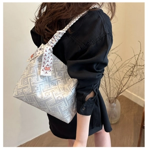 Detail of silver jacquard tote bag with braided handle and red geometric silk scarf decor