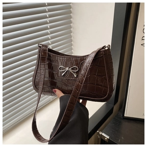 Detail of glossy chocolate brown crocodile pattern leather with silver bow clasp